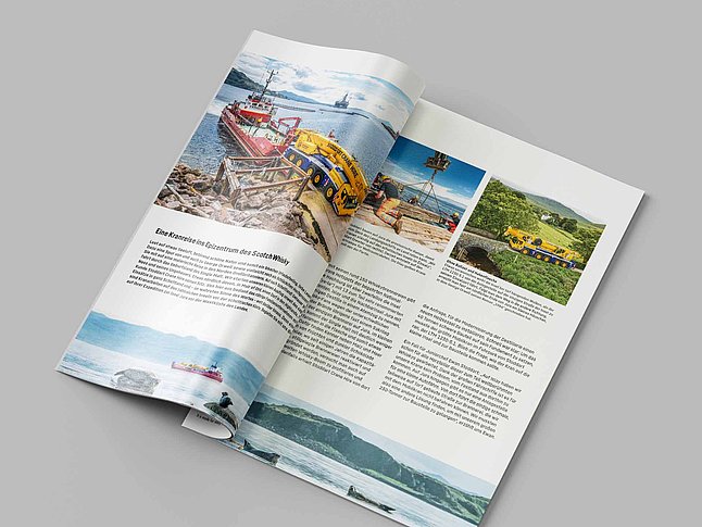 Aufgeschlagenes Magazin mit Bildern von Baumaschinen und Landschaften auf hellgrauem Hintergrund.